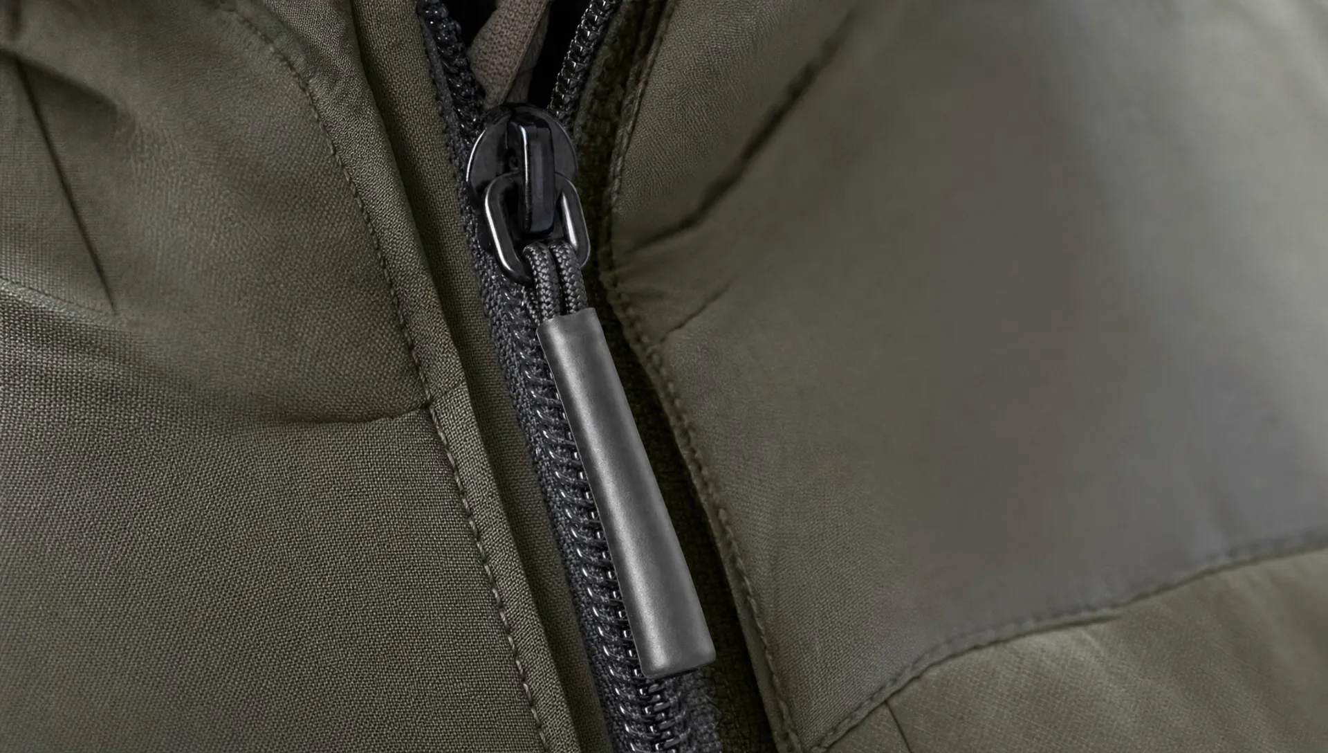 Close-up of a jacket zipper with a cord pull covered in heat shrink tubing, showing a thicker grip against outdoor fabric.