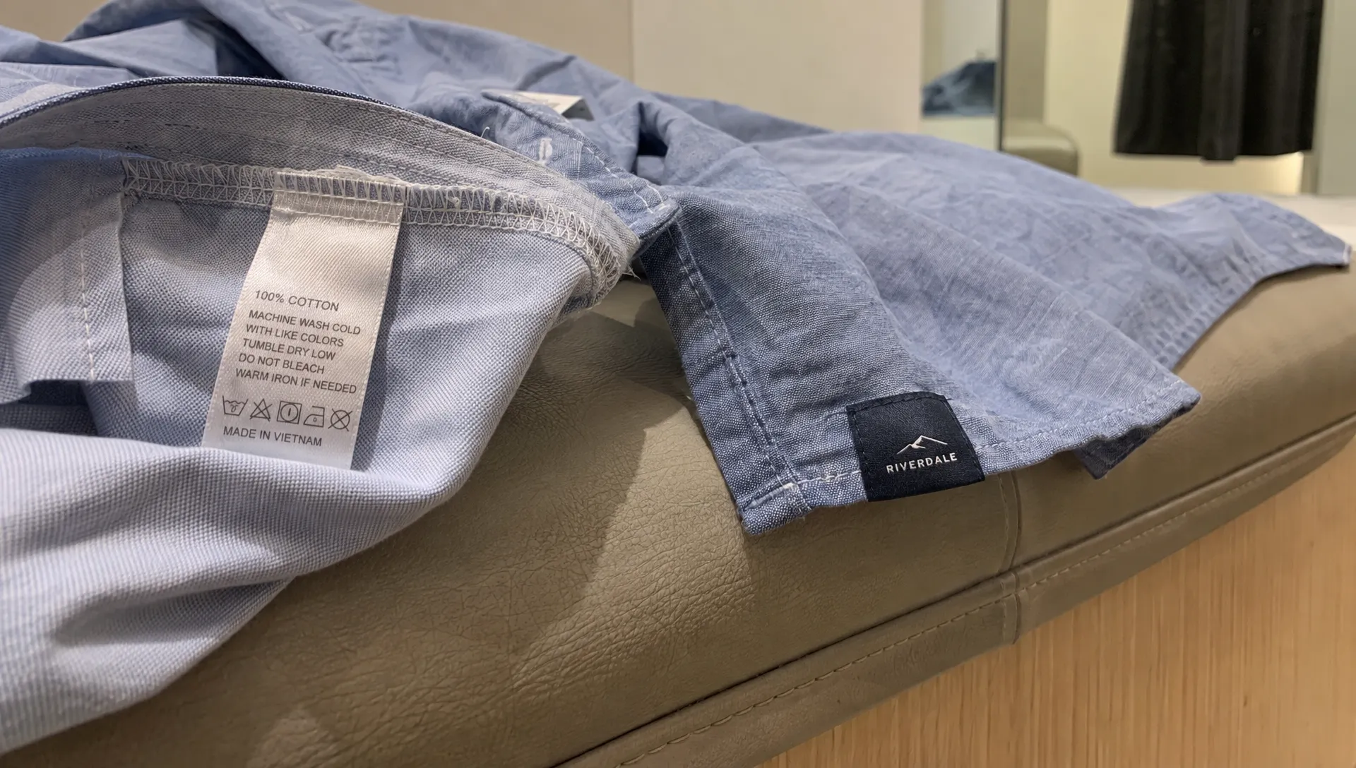 An inside-out shirt shows its folded label edge and attachment stitches beside a small exterior hem label.